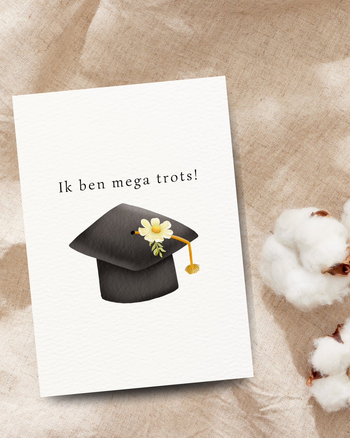 Afstudeerkaart met de tekst ‘Ik ben mega trots!’ en een zwarte afstudeerhoed met witte bloem