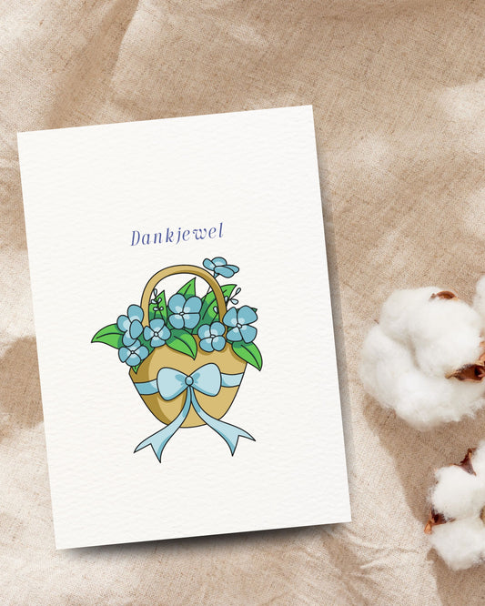 Bedankkaart met de tekst ‘Dankjewel’ en een bloemenmand met blauwe bloemen en strik