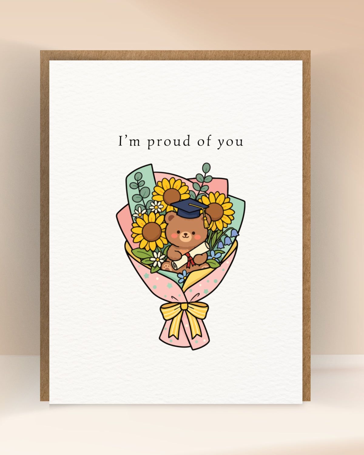 Afstudeerkaart met de tekst ‘I’m proud of you’ en een beer met diploma tussen zonnebloemen en andere bloemen